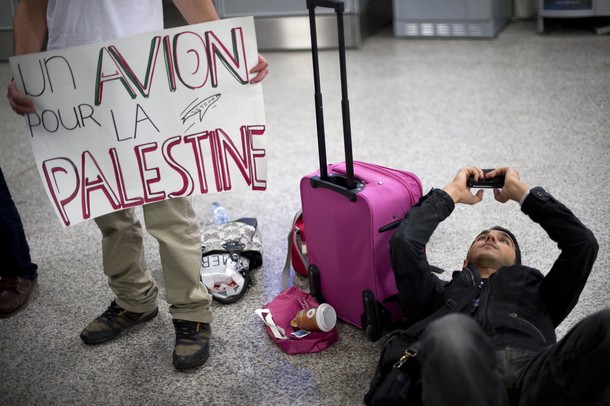 A Pro-Palestinian activists holds a placard reading in French "A plane for Palestine" during a protest at Geneva airport on April 15, 2012 in Geneva. Several dozen pro-Palestinian activists protested at Geneva airport, saying authorities prevented them from boarding a Tel Aviv-bound flight as part of a "fly-in" that Israel has vowed to block.    AFP PHOTO/ FABRICE COFFRINI