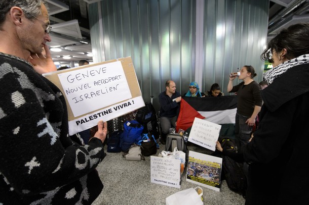 Pro-Palestinian activists hold placards reading "Geneva, new Israeli airport. Palestine will live" as they protest at Geneva airport on April 15, 2012 in Geneva. Several dozen pro-Palestinian activists protested at Geneva airport, saying authorities prevented them from boarding a Tel Aviv-bound flight as part of a "fly-in" that Israel has vowed to block.    AFP PHOTO/ FABRICE COFFRINI