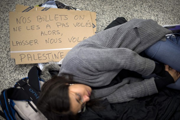 A pro-Palestinian activist has a rest next to a placard reading "We have not stolen our tickets so let us fly" during a protest at Geneva airport on April 15, 2012 in Geneva. Several dozen pro-Palestinian activists protested at Geneva airport, saying authorities prevented them from boarding a Tel Aviv-bound flight as part of a "fly-in" that Israel has vowed to block.    AFP PHOTO/ FABRICE COFFRINI
