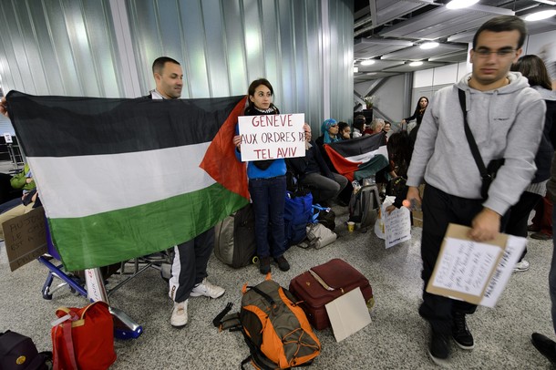 Pro-Palestinian activists hold placards reading "Geneva gets orders from Israel" at Geneva airport on April 15, 2012 in Geneva. Several dozen pro-Palestinian activists protested at Geneva airport, saying authorities prevented them from boarding a Tel Aviv-bound flight as part of a "fly-in" that Israel has vowed to block.    AFP PHOTO/ FABRICE COFFRINI