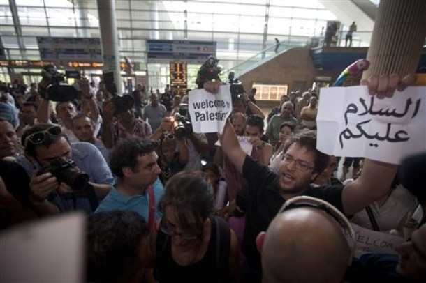 A locally-based pro-Palestinian activist holds signs in English and Arabic reading "Welcome to Palestine" at Ben-Gurion international airport near Tel Aviv, Israel Friday, July 8, 2011. Scores of pro-Palestinian protesters trying to reach Israel were blocked at airports in Europe and two American activists who arrived in Israel were deported early Friday, Israeli officials said, after Israel increased security at the airport ahead of the activists' arrival and asked foreign airlines to prevent blacklisted travelers from boarding Israel-bound flights. (AP Photo/Oded Balilty)