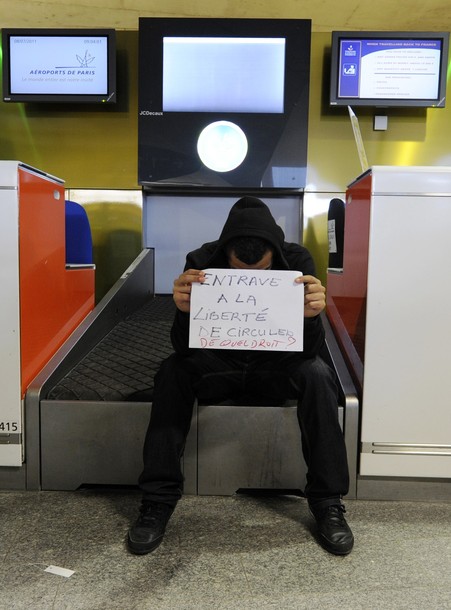 A man holding a sign which reads "Hindrance to free movement. On what grounds?" sits at a check-in counter at Charles-de-Gaulle airport in Roissy near Paris July 8, 2011. A Hungarian airline stopped dozens of French activists heading for a pro-Palestinian "fly-in" in Israel from boarding a plane in Paris on Thursday. Some 600 people from around Europe, of which roughly 350 are from France, are trying to visit the city of Bethlehem at the invitation of a Palestinian group in an operation dubbed "Welcome to Palestine".       REUTERS/Gonzalo Fuentes